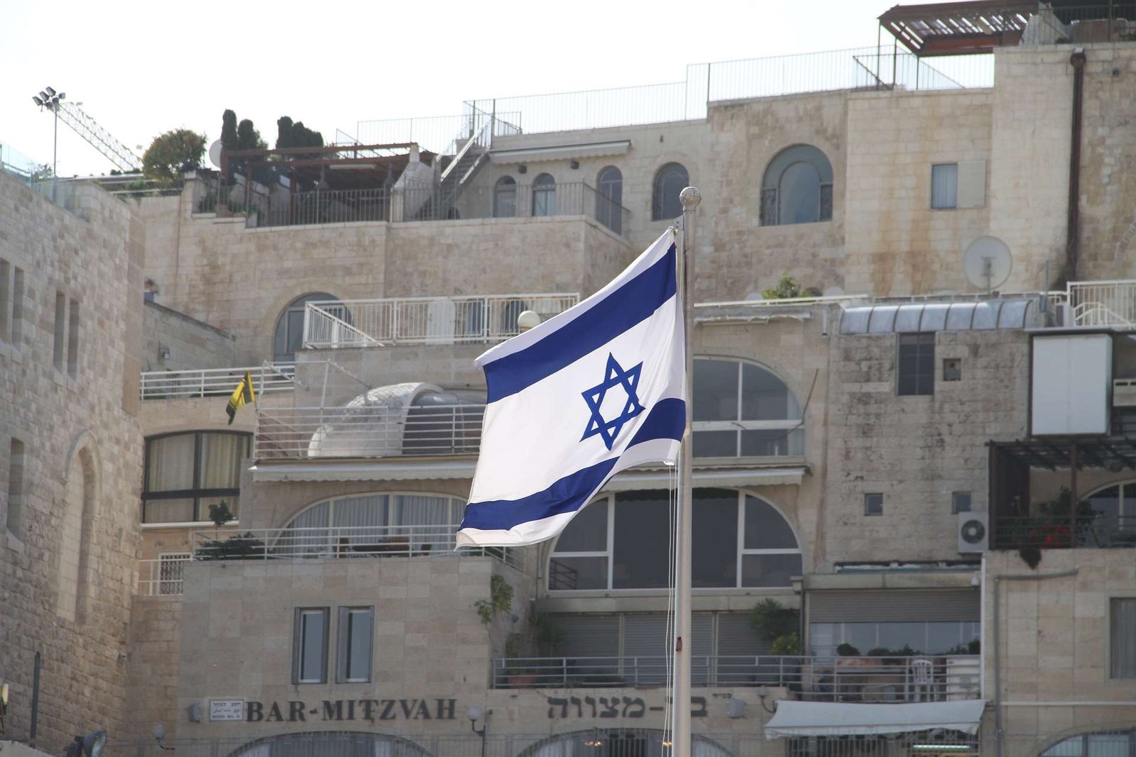 Israeli flag flying in Jerusalem’s Old City with stone buildings in the background. Title: Jerusalem, Israel — National Flag in the Old City