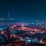 Panoramic night view of Yerevan’s illuminated cityscape with the Yerevan TV Tower glowing atop the hill in the background.