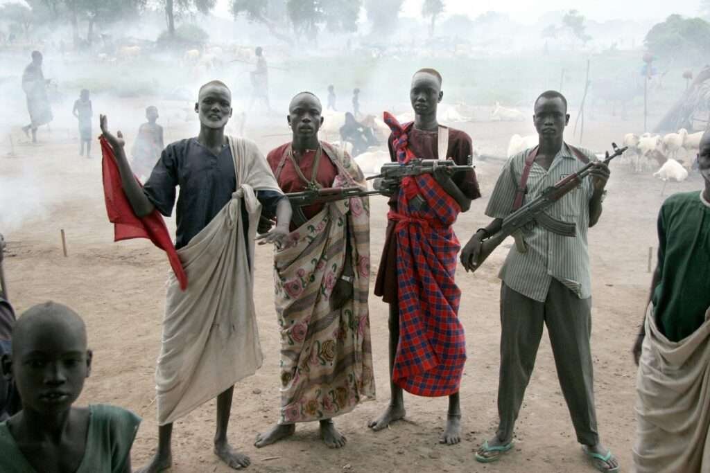 Dinka youth guarding cattle at a dusty South Sudan camp