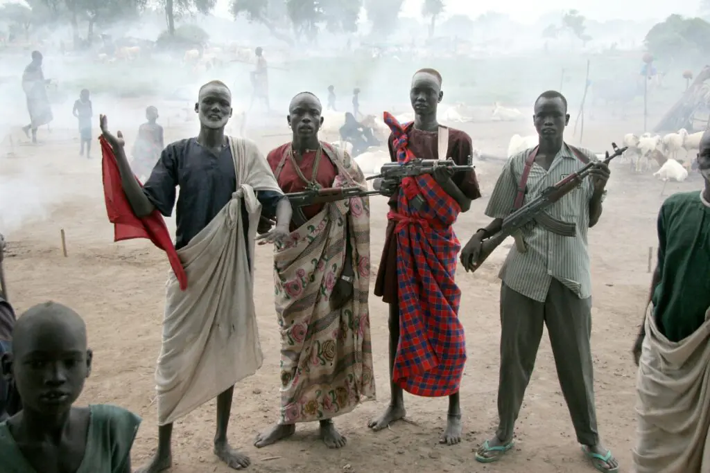 Dinka youth guarding cattle at a dusty South Sudan camp