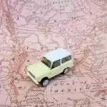 Miniature SUV on a vintage map of North America, symbolizing travel across the continent’s 23 countries and their capitals.