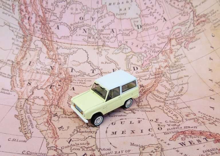 Miniature SUV on a vintage map of North America, symbolizing travel across the continent’s 23 countries and their capitals.