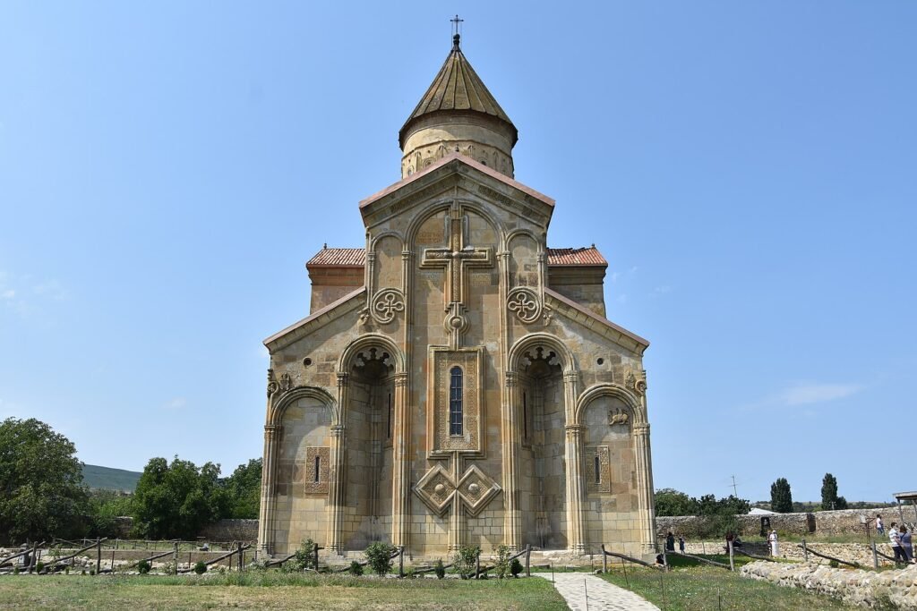 Samtavisi Cathedral, an 11th-century Georgian Orthodox church near Kaspi in Shida Kartli, Georgia—front façade with carved stone and conical dome under a clear sky.