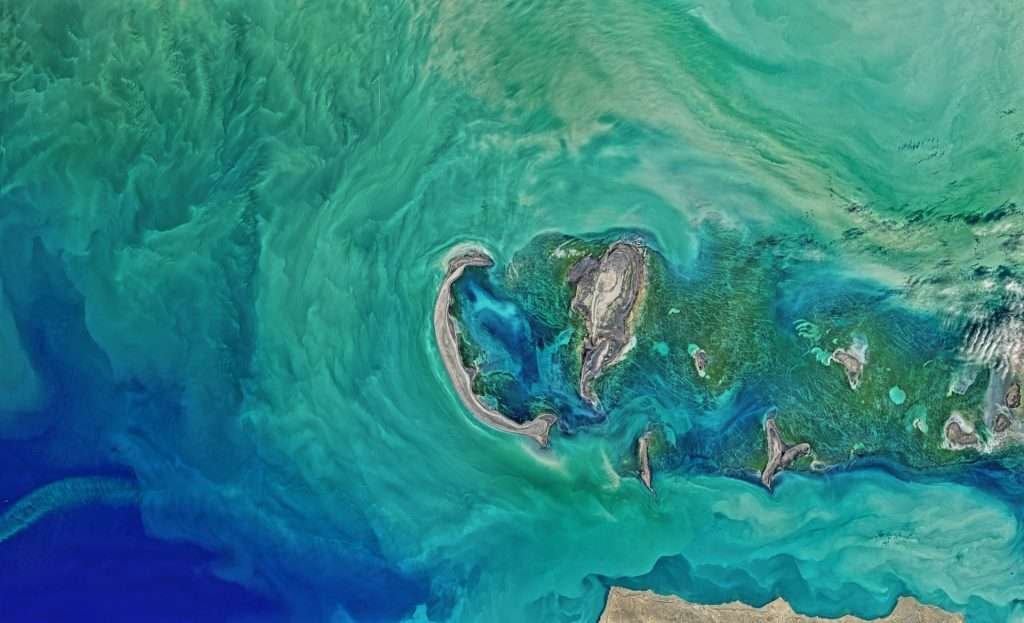 Aerial view of the Caspian Sea showcasing its vast turquoise waters and the diverse topography of its surrounding landscapes.