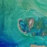 Aerial view of the Caspian Sea showcasing its vast turquoise waters and the diverse topography of its surrounding landscapes.
