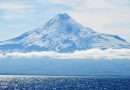 Majestic snow-capped volcano towering over the glistening ocean