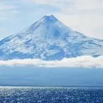Majestic snow-capped volcano towering over the glistening ocean