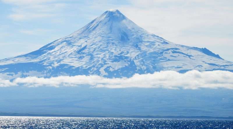 Majestic snow-capped volcano towering over the glistening ocean