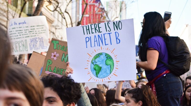 Crowd at a climate protest holding a sign that reads “There is no Planet B” with a hand-drawn Earth
