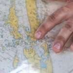 A hand pointing at a detailed world map highlighting various geographical features.