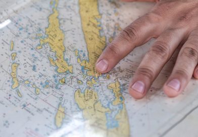 A hand pointing at a detailed world map highlighting various geographical features.