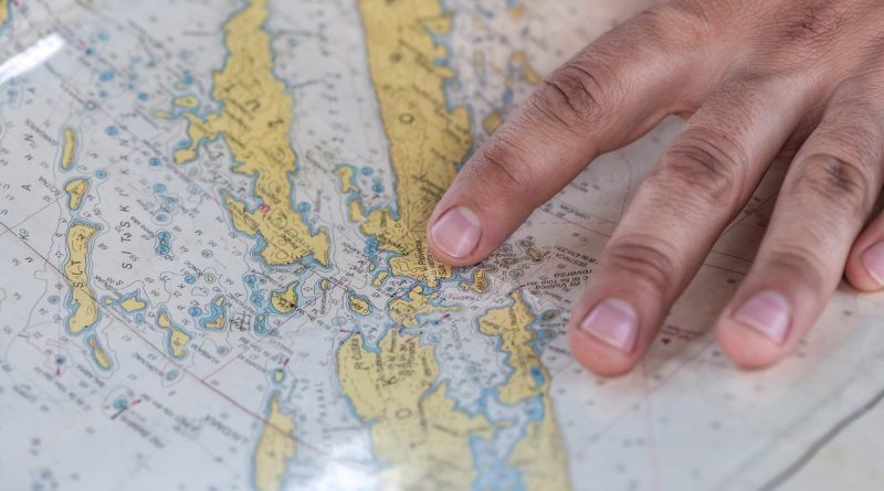 A hand pointing at a detailed world map highlighting various geographical features.