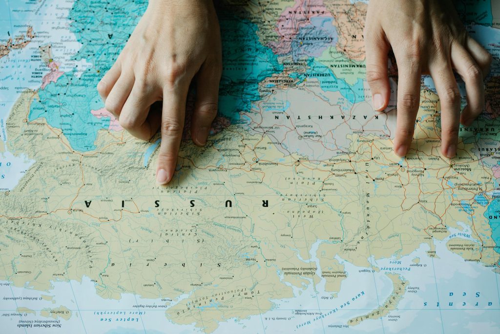 Hands pointing at Russia on a world map