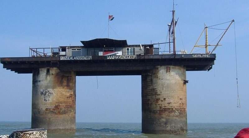 Sealand sea-fort platform on twin concrete towers above the North Sea, displaying its flag and antenna structures.