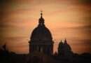 Silhouette of St. Peter’s Basilica dome against a vivid sunset sky in Vatican City