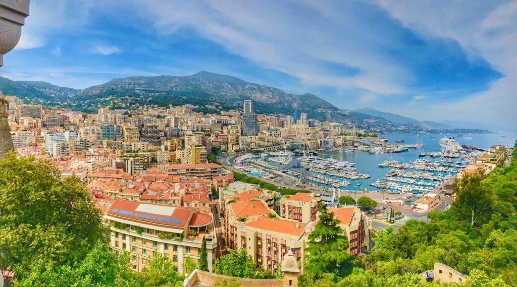 Panoramic view of Monaco with Port Hercule marina, densely packed high-rises of Monte Carlo and La Condamine climbing steep hills, and the Mediterranean and Maritime Alps in the background