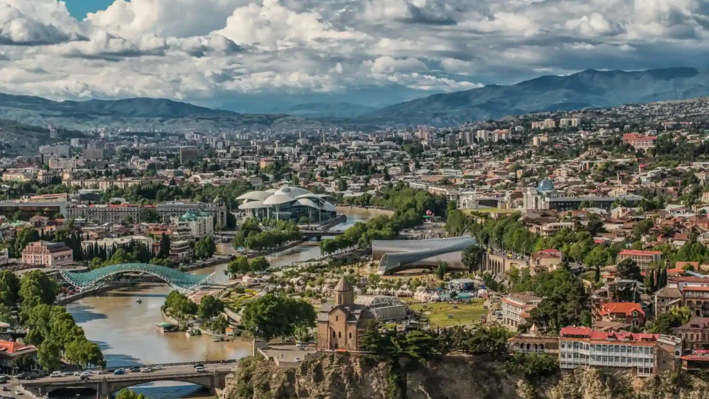 Panoramic view of Tbilisi with the Mtkvari River and surrounding hills.