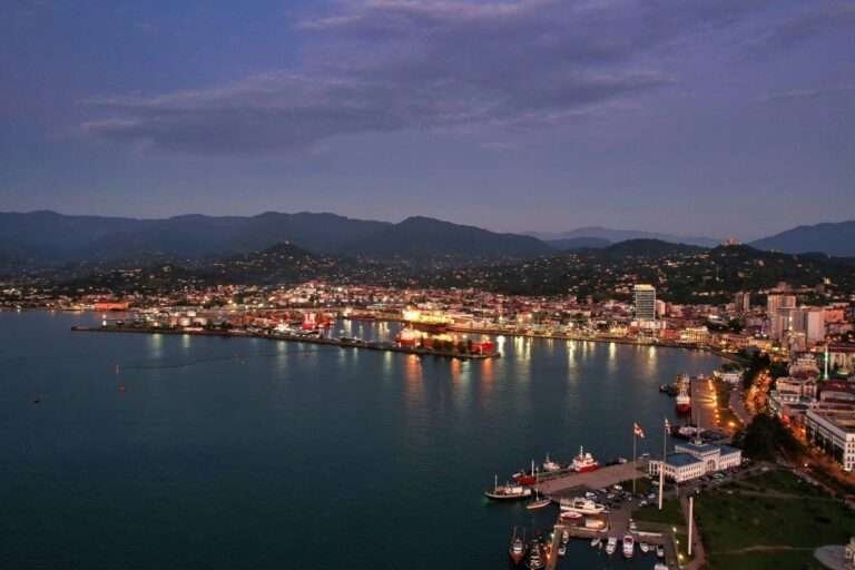 Batumi Black Sea coastline at dusk with illuminated port and mountains in the background