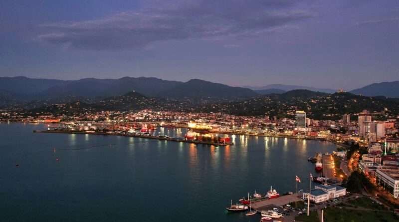 Batumi Black Sea coastline at dusk with illuminated port and mountains in the background
