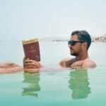 Man floating and reading a book in the Dead Sea, Israel, demonstrating effortless buoyancy in hypersaline water