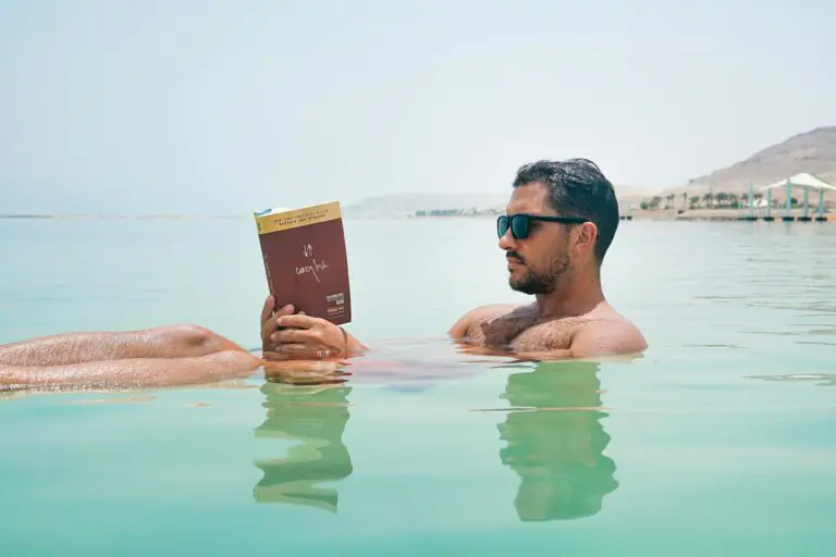 Man floating and reading a book in the Dead Sea, Israel, demonstrating effortless buoyancy in hypersaline water