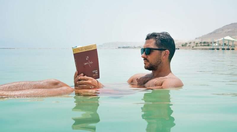 Man floating and reading a book in the Dead Sea, Israel, demonstrating effortless buoyancy in hypersaline water