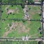Aerial photograph of Gonio Fortress showing its rectangular stone walls, towers, and excavated interior structures surrounded by greenery.