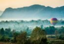 Colorful hot air balloon floating over misty fields and limestone mountains in Vang Vieng, Laos