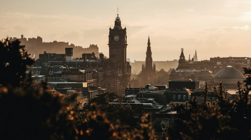 Sunset skyline of Edinburgh, Scotland, with the Balmoral Clock Tower, the gothic Scott Monument, and Edinburgh Castle rising above Old and New Town rooftops.