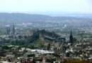 Aerial view of Edinburgh city with Edinburgh Castle on Castle Rock, surrounded by historic spires and stone buildings.