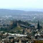 Aerial view of Edinburgh city with Edinburgh Castle on Castle Rock, surrounded by historic spires and stone buildings.