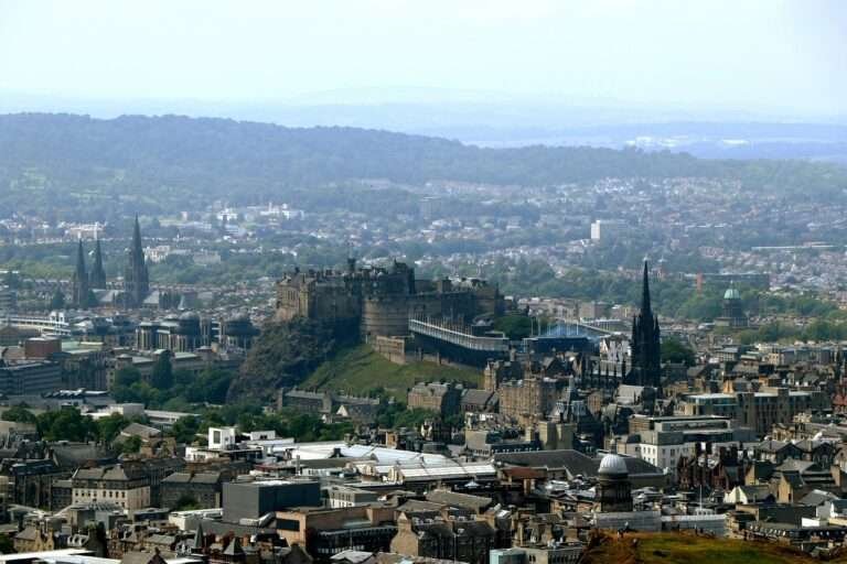 Aerial view of Edinburgh city with Edinburgh Castle on Castle Rock, surrounded by historic spires and stone buildings.
