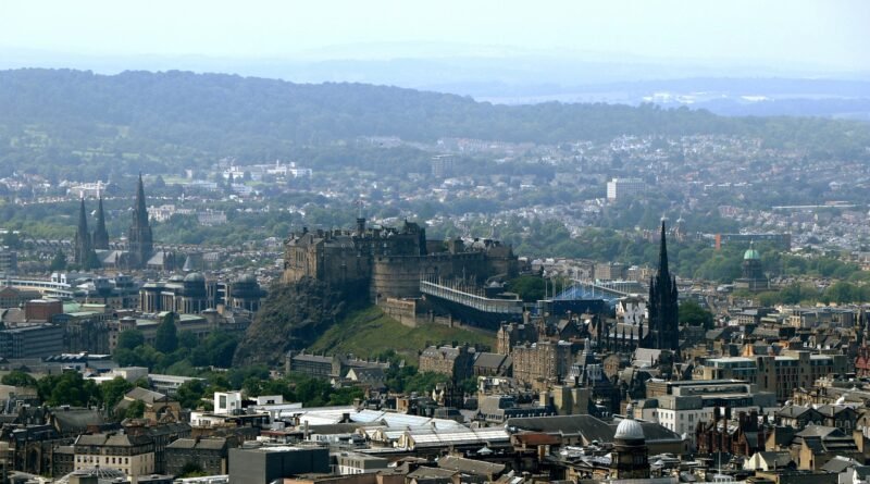 Aerial view of Edinburgh city with Edinburgh Castle on Castle Rock, surrounded by historic spires and stone buildings.