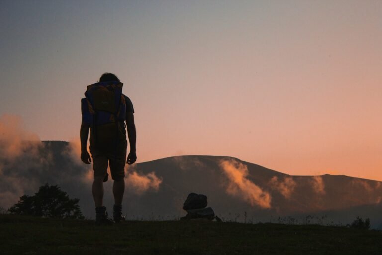 Solo traveler with backpack hiking at sunrise in the mountains, symbolizing independence and adventure