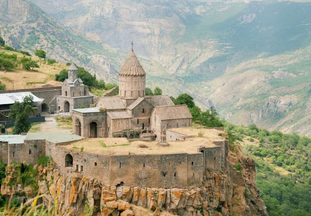 Aerial view of Tatev Monastery in Armenia with stone walls and conical dome above Vorotan Gorge