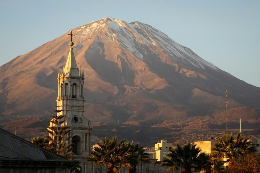 Misti volcano rising behind a colonial church tower at golden hour, Arequipa, Peru.