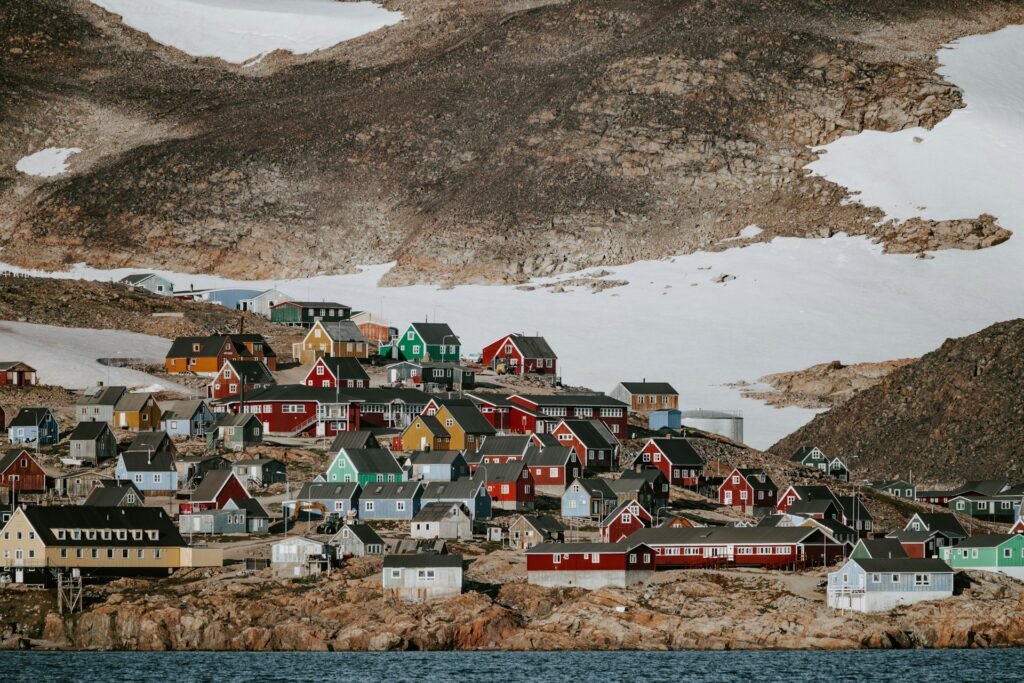 Colorful houses of Ittoqqortoormiit on rocky coast with late-season snow
