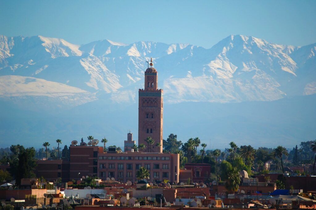Koutoubia Mosque minaret with snow-capped High Atlas Mountains, Marrakech, Morocco.