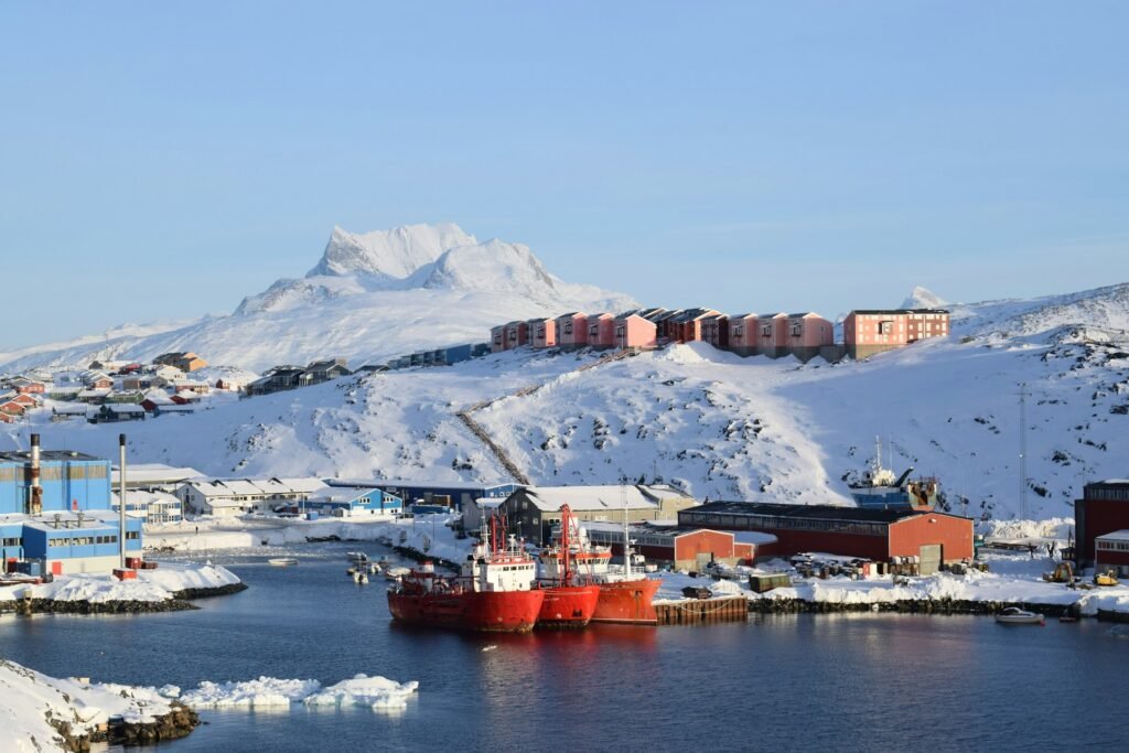 Nuuk harbor with red vessels and colorful housing beneath Sermitsiaq mountain