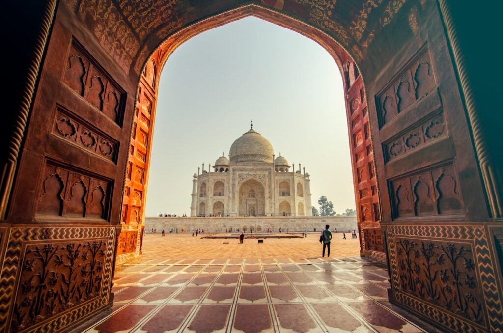 Taj Mahal framed through the ornate red-sandstone gateway arch at sunrise, Agra, India.