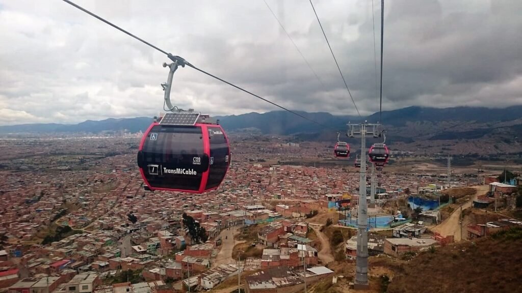 TransMiCable cabin with rooftop solar panel crossing over Ciudad Bolívar, Bogotá, with Andean mountains beyond