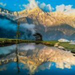 Sunrise on the Dhauladhar Range reflected in a hilltop pond at Triund, Himachal Pradesh, India.