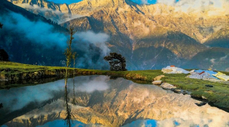 Sunrise on the Dhauladhar Range reflected in a hilltop pond at Triund, Himachal Pradesh, India.