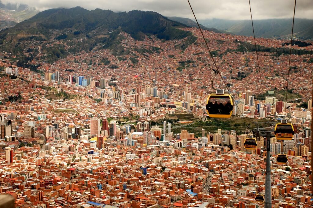 Mi Teleférico gondolas gliding above the dense cityscape of La Paz with mountains in the background.