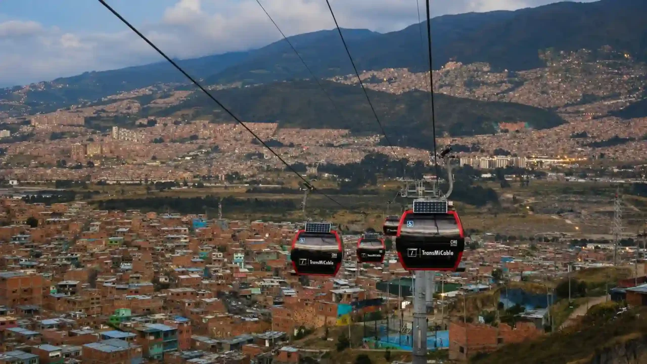 Red TransMiCable gondolas traveling above Ciudad Bolívar’s hillside neighborhoods in Bogotá, Colombia.