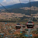Red TransMiCable gondolas traveling above Ciudad Bolívar’s hillside neighborhoods in Bogotá, Colombia.