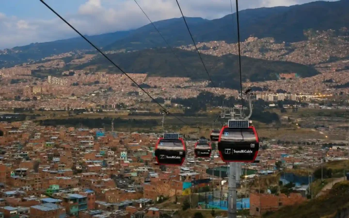 Red TransMiCable gondolas traveling above Ciudad Bolívar’s hillside neighborhoods in Bogotá, Colombia.