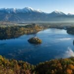 Lake Bled, Slovenia—calm blue water with a small island church, autumn forests, morning mist, and the snow-capped Julian Alps in the background; a clear example of a natural inland lake.