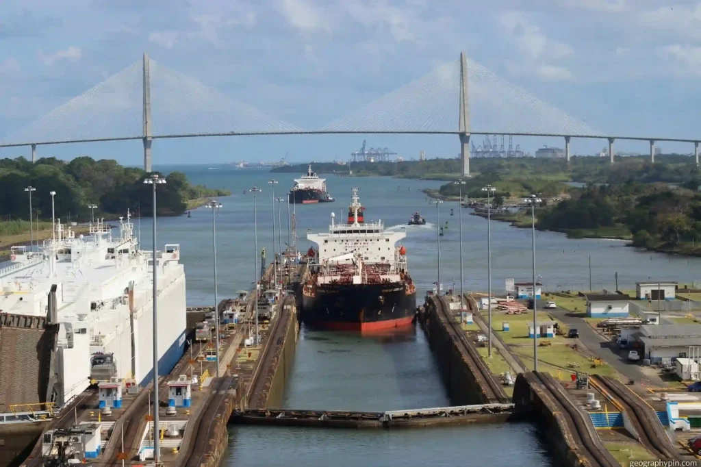 Cargo ships moving through the Panama Canal locks beneath the Atlantic Bridge in Panama.