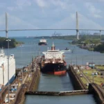 Cargo ships moving through the Panama Canal locks beneath the Atlantic Bridge in Panama.